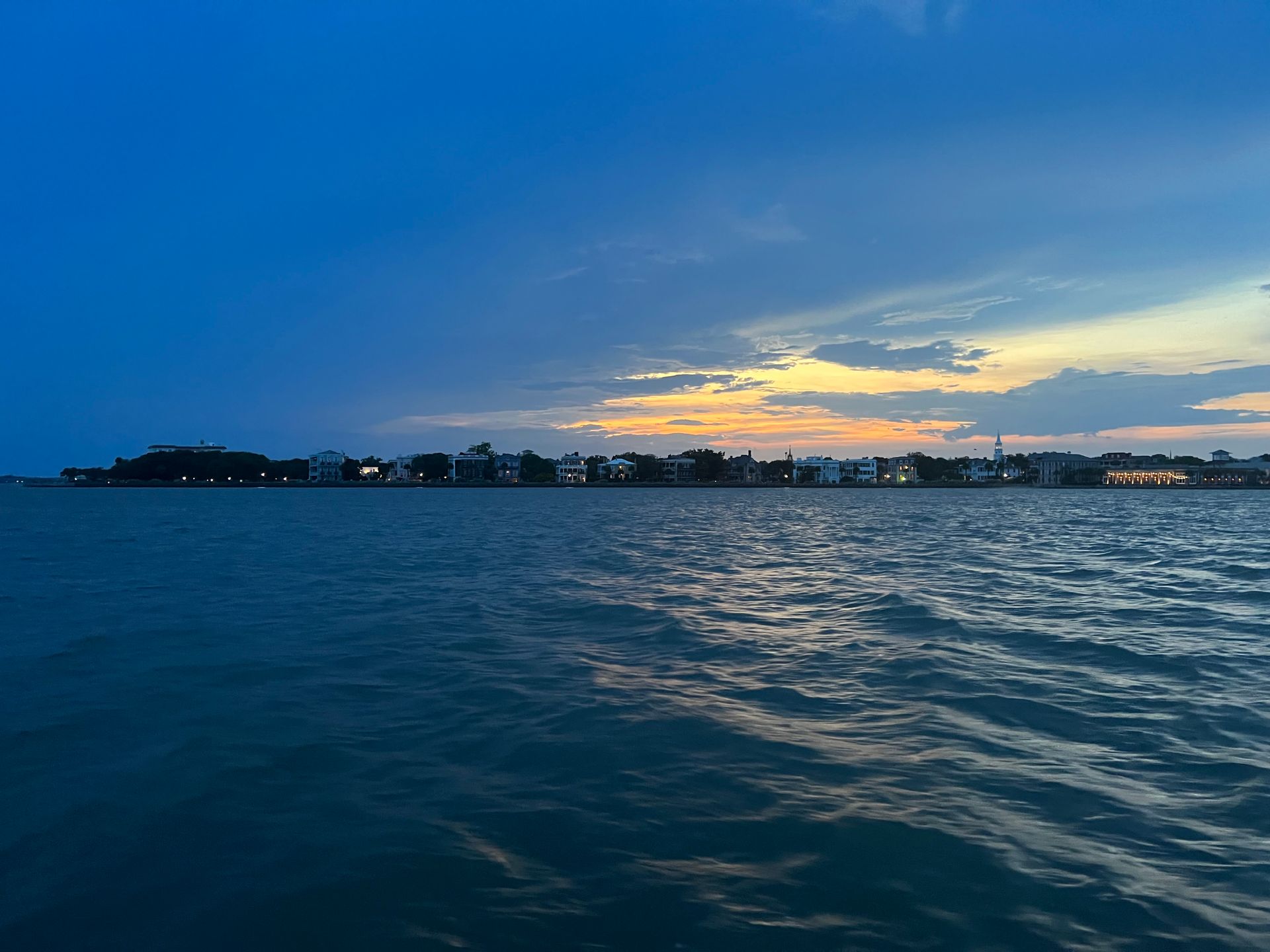 A large body of water with a city in the background at sunset.