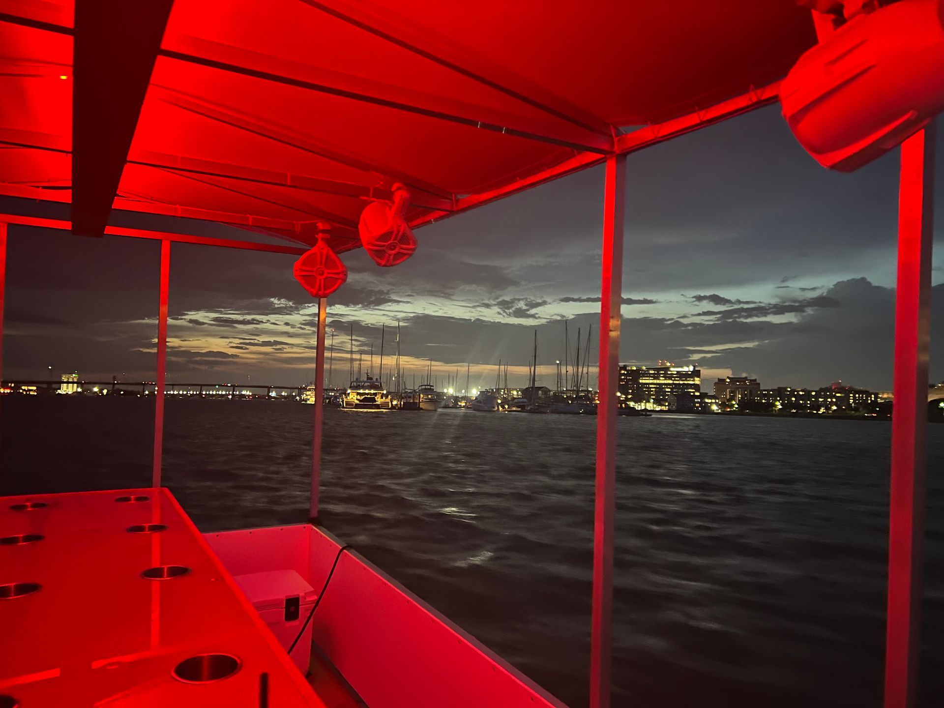 A boat with a red canopy is floating on the water at night