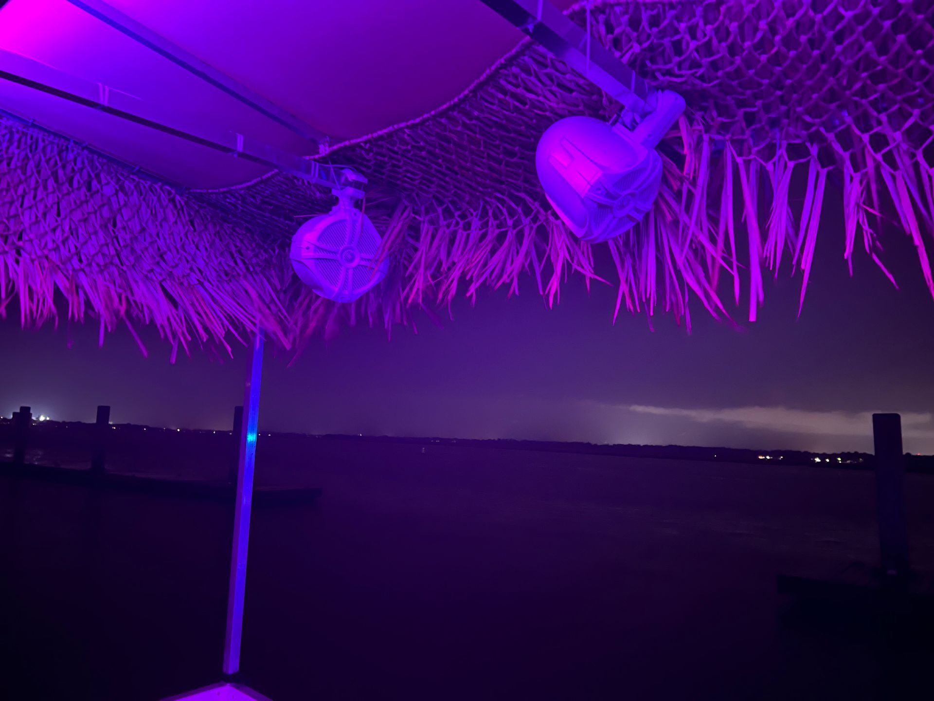 A purple umbrella is lit up with purple lights at night.