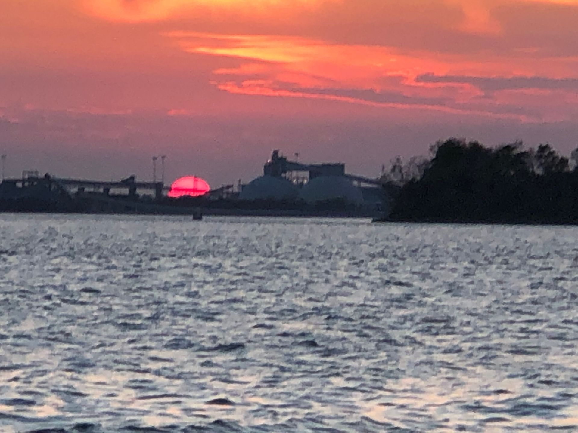 A sunset over a body of water with a bridge in the background