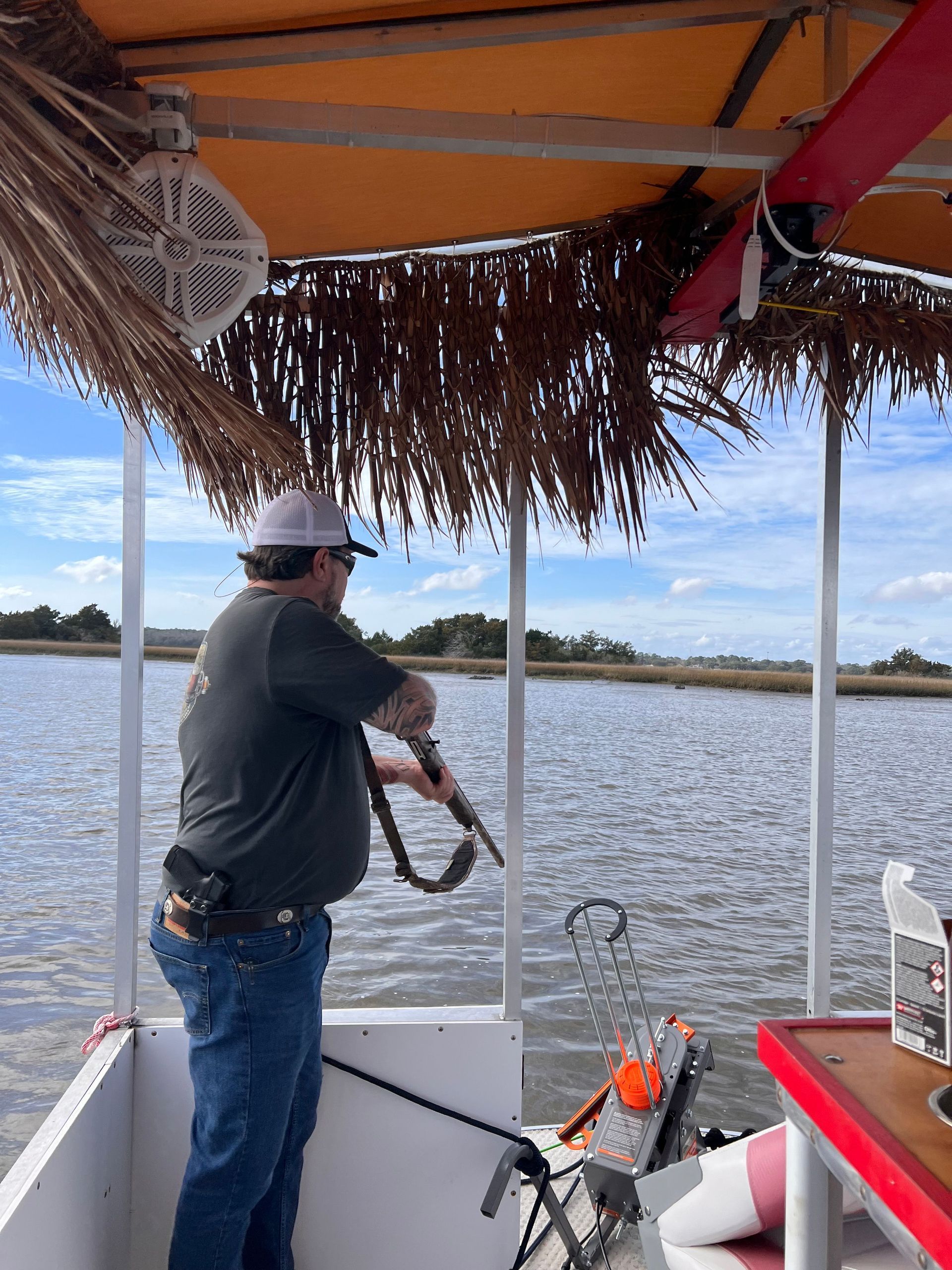 A man is fishing on a boat with a thatched roof