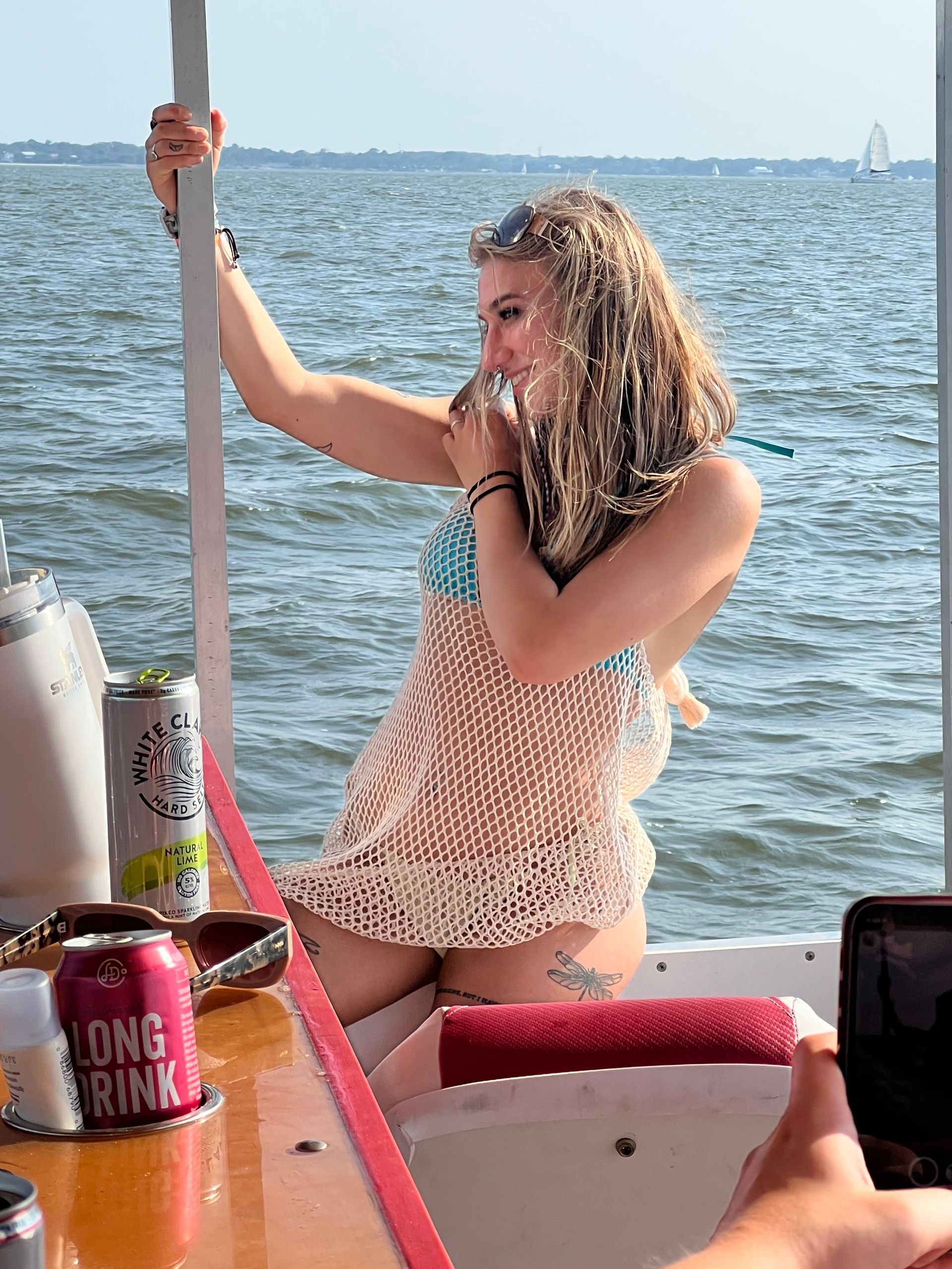 A woman is sitting on a boat drinking from a can of long brink beer.