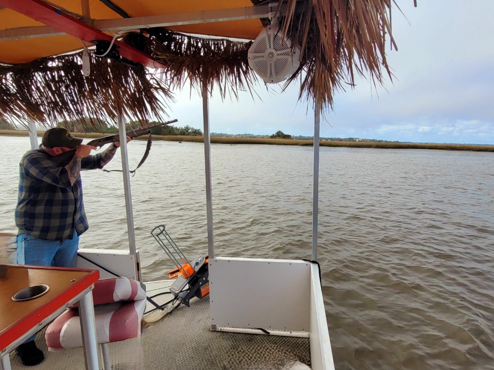 A man in a plaid shirt is standing on a boat in the water