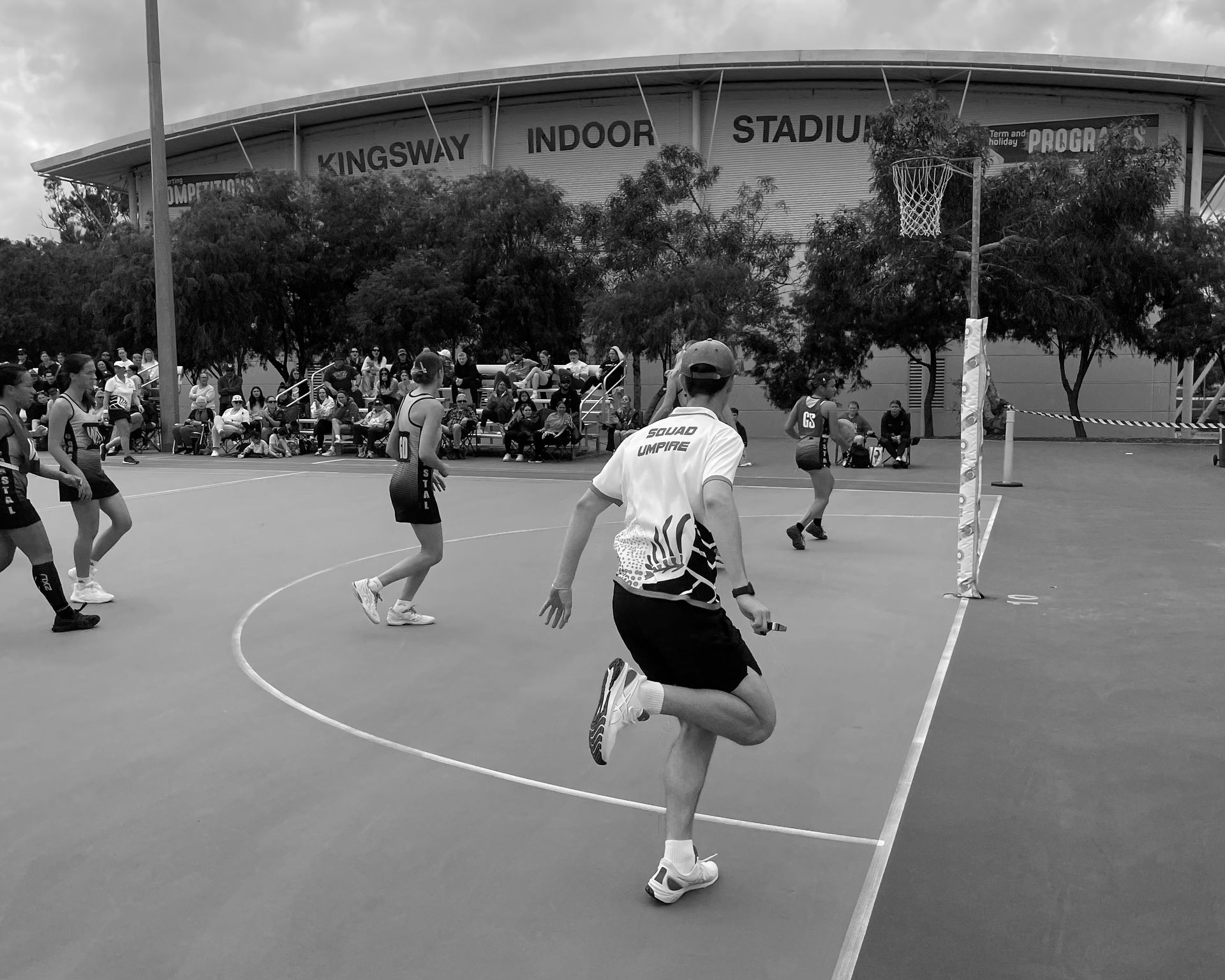 A black and white photo of people playing indoor basketball
