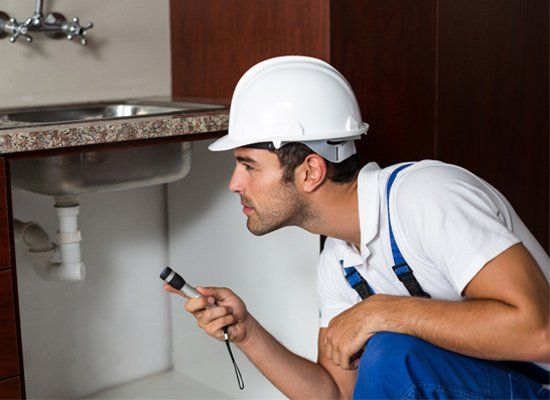 Real Estate Home Inspection — in Orange County, CA Real Estate Home Inspection — Real Estate Home Inspector Using Flashlight in Kitchen in Orange County, CA