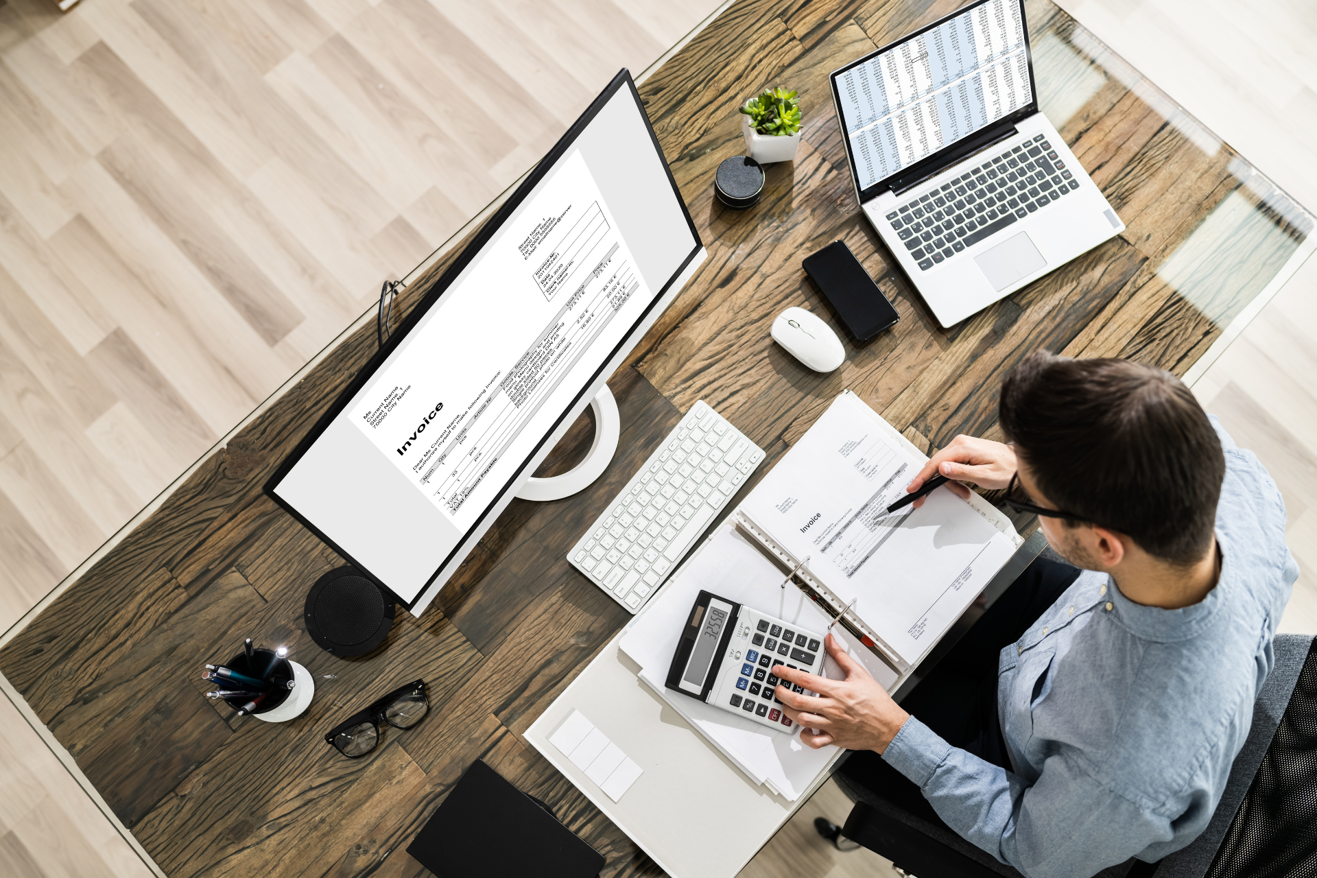 A man is sitting at a desk with a computer and a laptop.