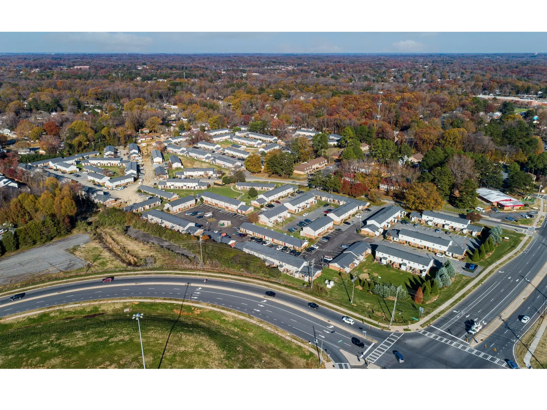 Aerial view of a large apartment community with multiple buildings, parking lots, and trees.