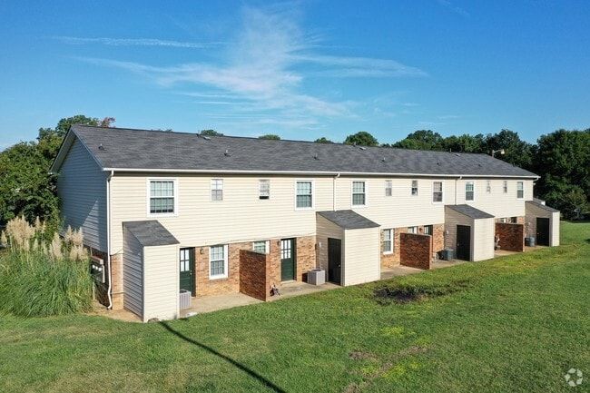Townhouse complex, beige siding, brown brick, green grass, blue sky.