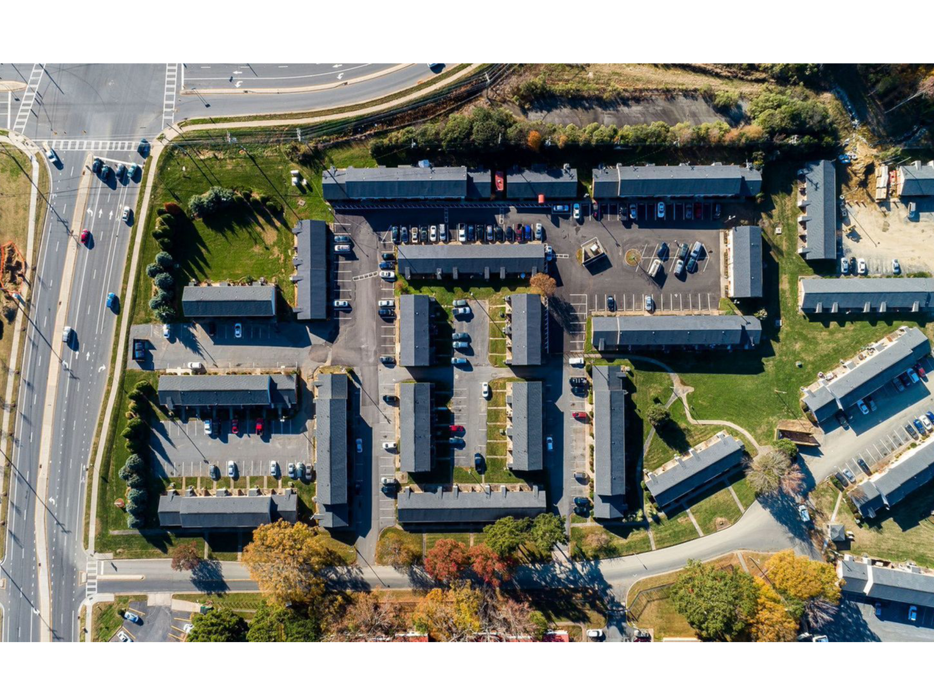 Aerial view of a multi-building apartment community with parking lots and roads.