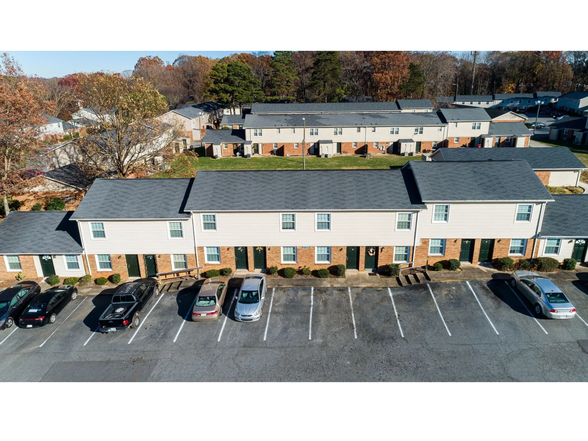 Aerial view of a townhouse-style apartment complex with brick fronts and parked cars.