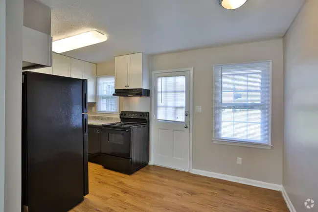 Kitchen with black appliances, white cabinets, and light wood-look flooring.