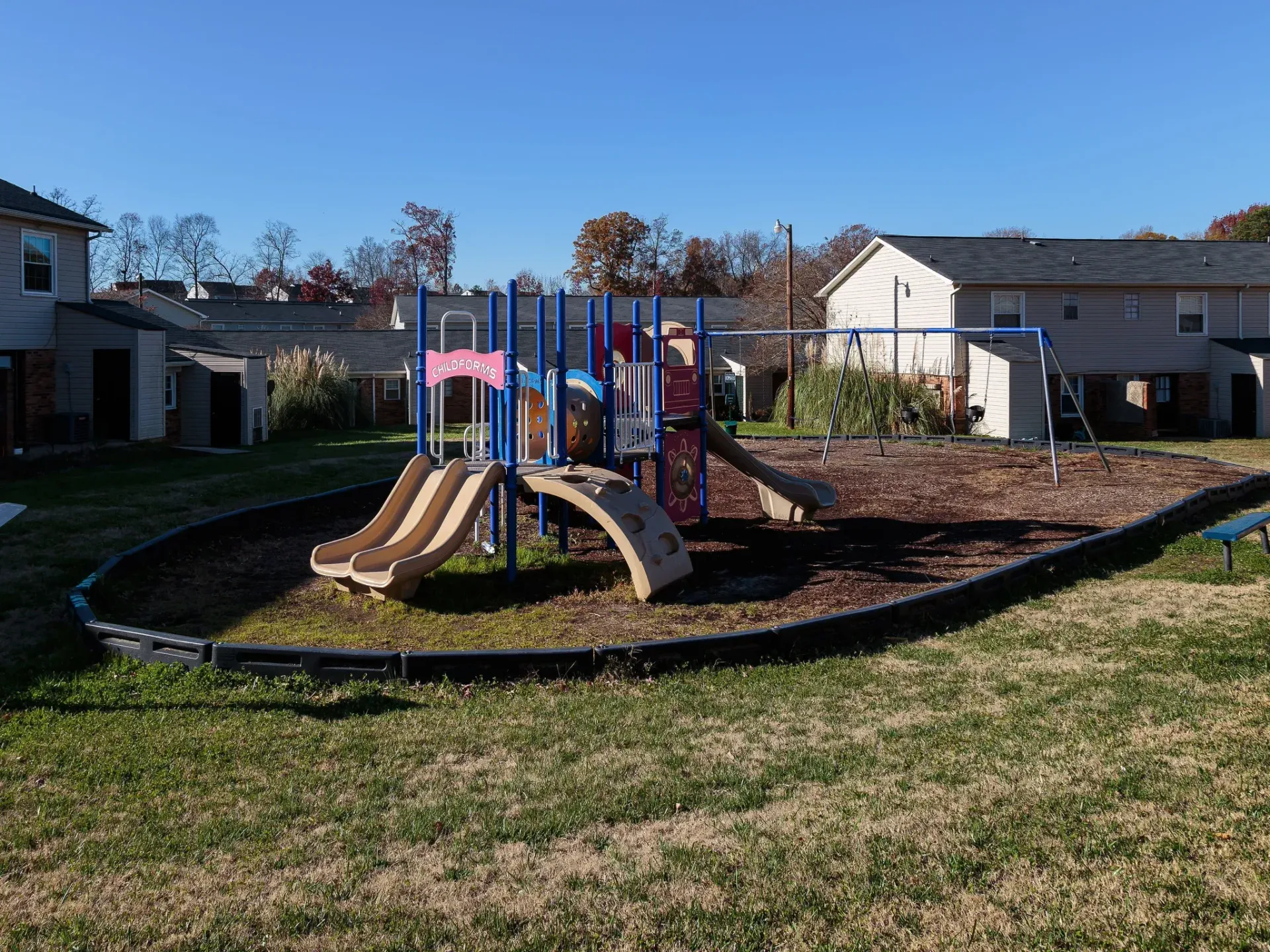 Playground with slides and swings in a community courtyard, with apartment buildings in the background.