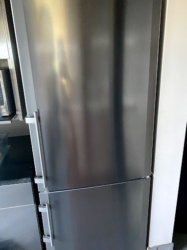 A stainless steel refrigerator is sitting in a kitchen next to a microwave.