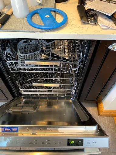 An empty dishwasher is sitting on a counter in a kitchen.