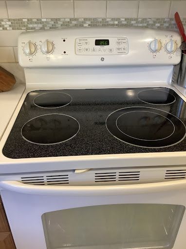 A white stove top oven is sitting on top of a kitchen counter.