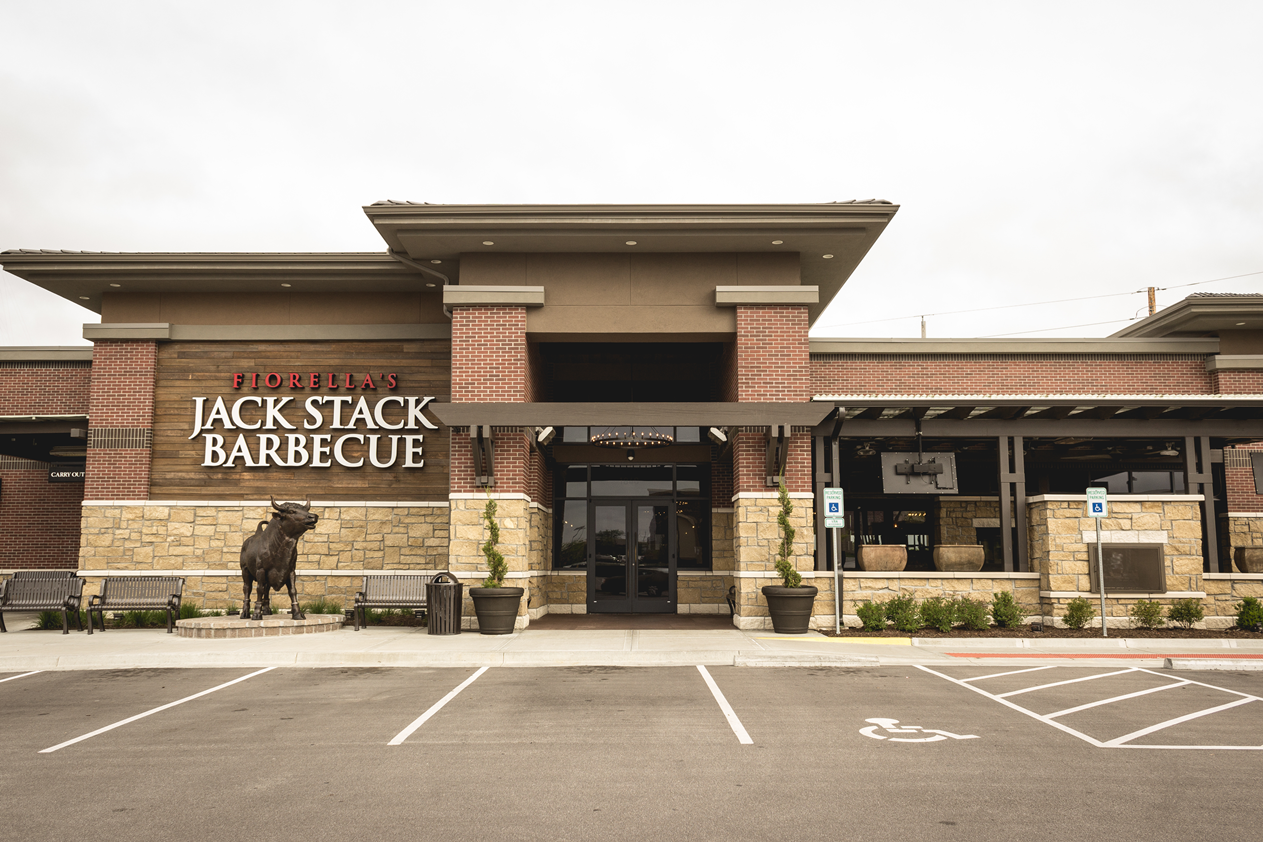 The front of a restaurant called jack stack barbecue with a parking lot in front of it.