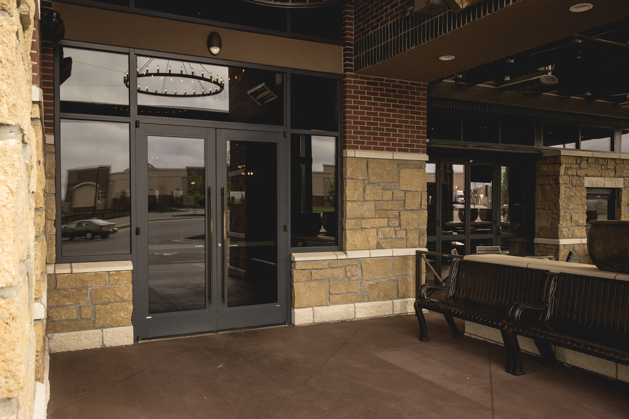 A brick building with a glass door and a bench in front of it.