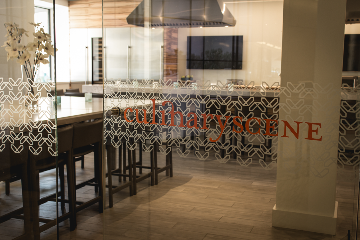 A glass door leading to a kitchen with a table and chairs.