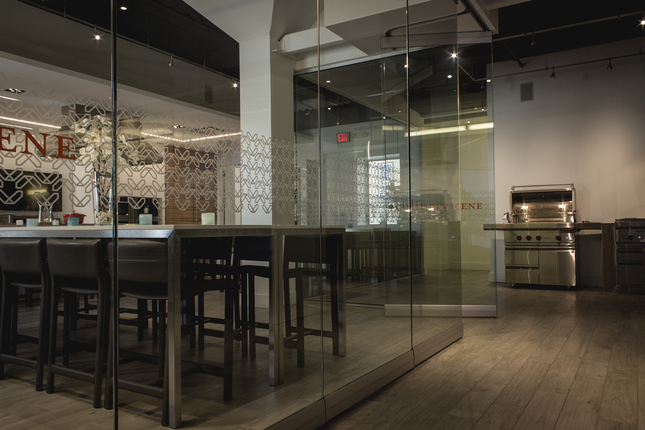 A restaurant with a table and stools in front of a glass wall.