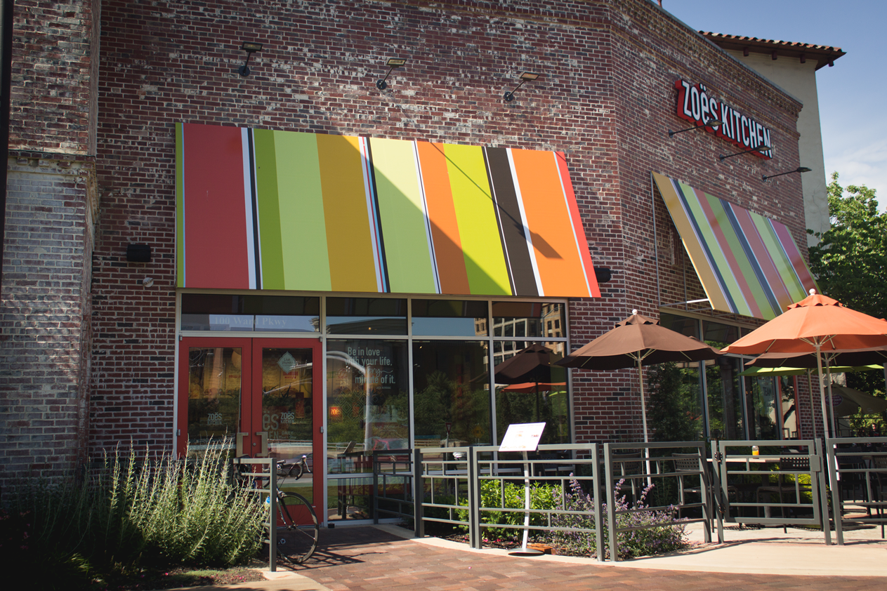 A restaurant with a colorful awning and umbrellas outside