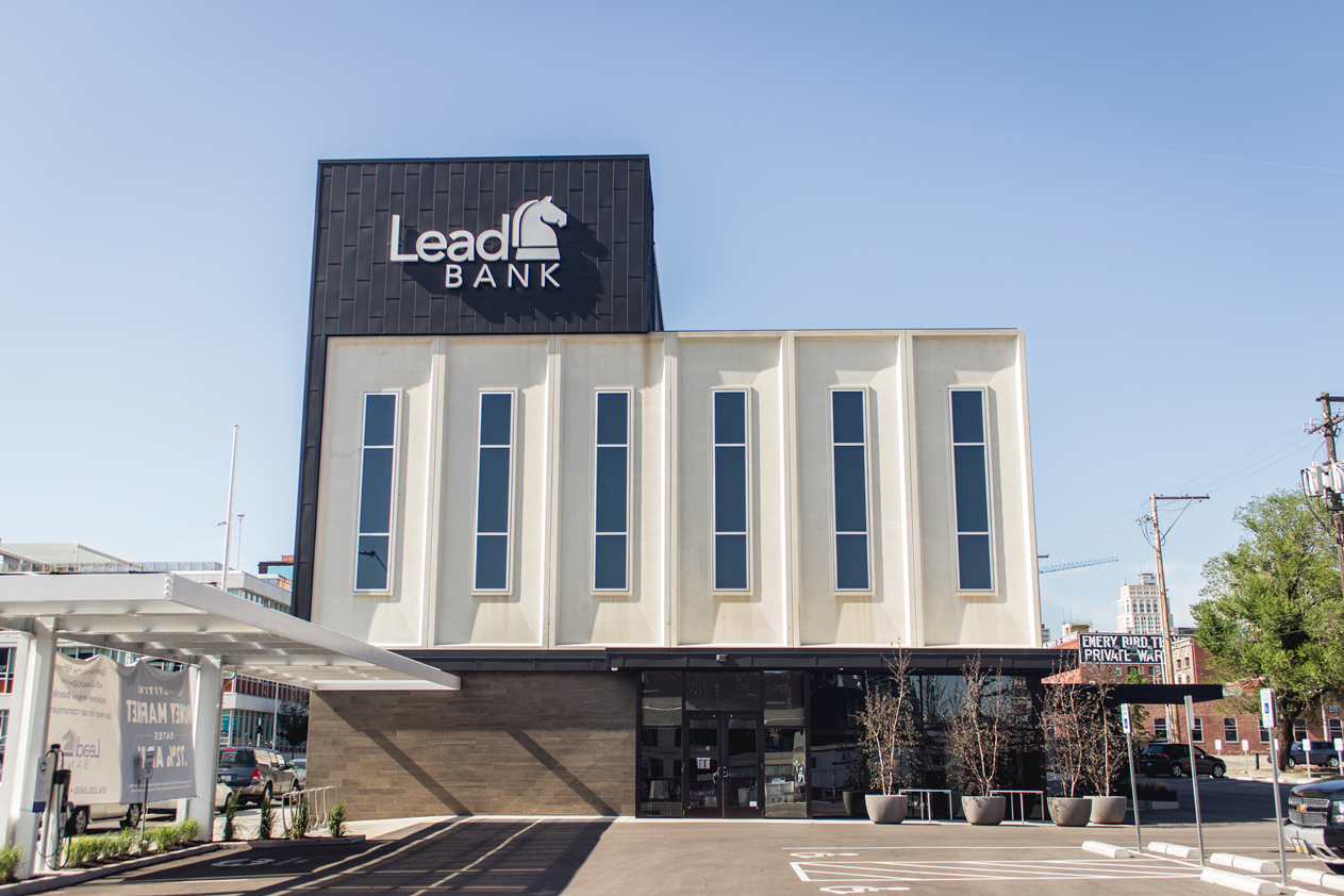 A lead bank building with a lot of windows and a parking lot in front of it.