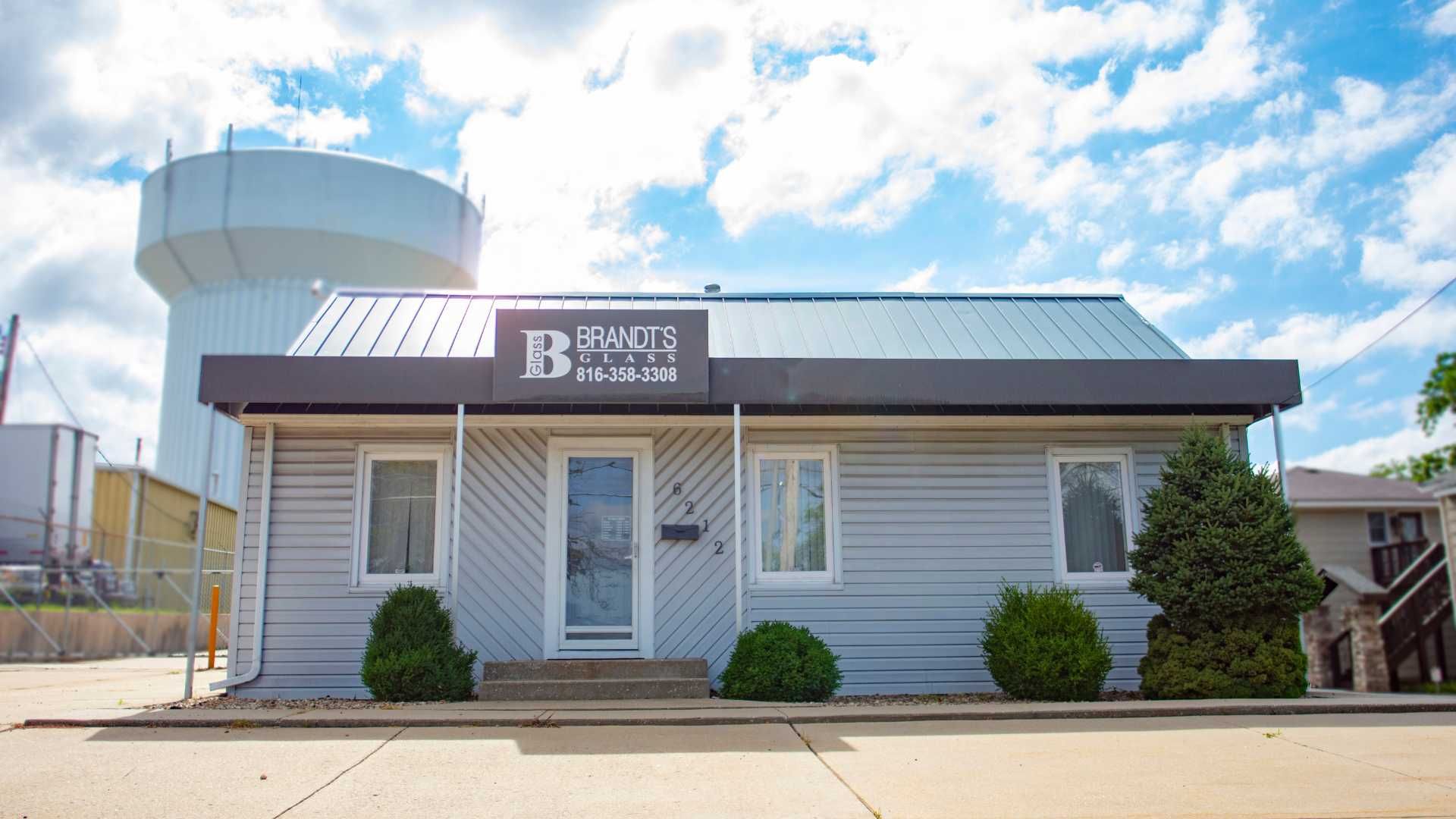 A small gray house with a water tower in the background.