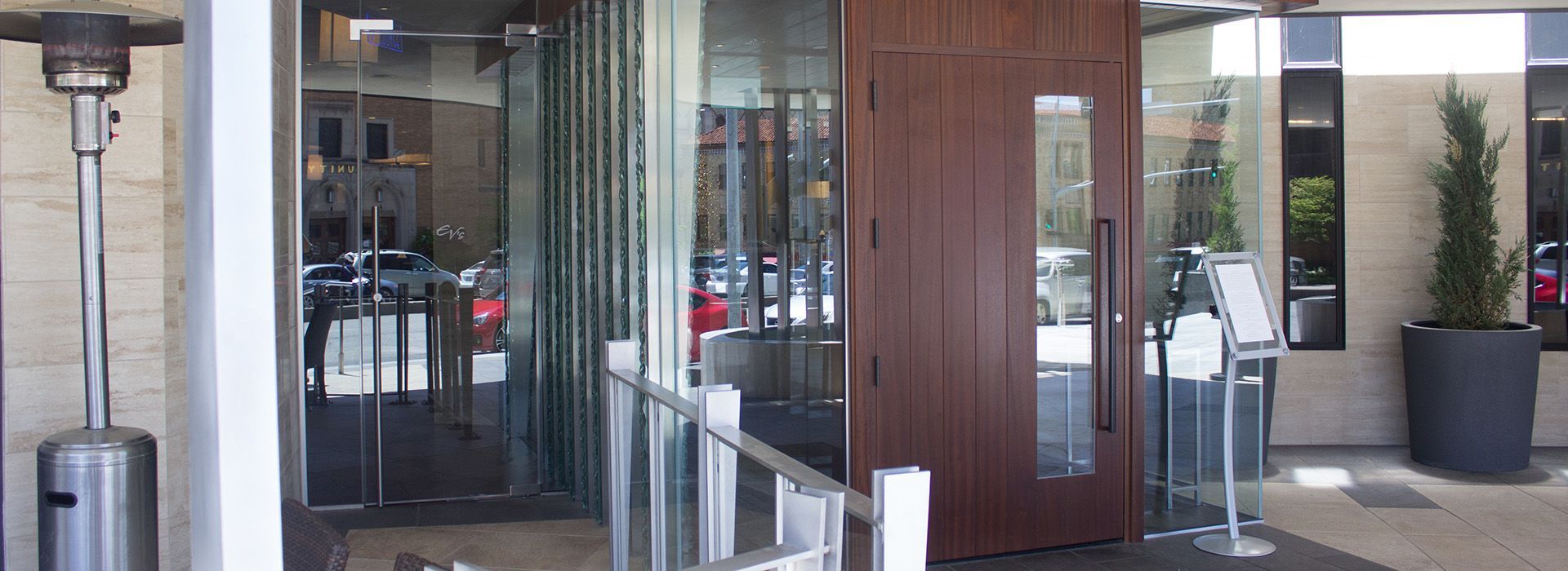 A large wooden door is surrounded by glass and a patio heater.