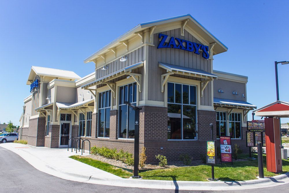 A fast food restaurant called zaxby 's is located on the corner of a street.