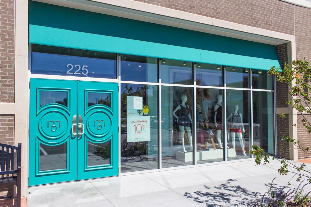 A store front with blue doors and a bench in front of it.