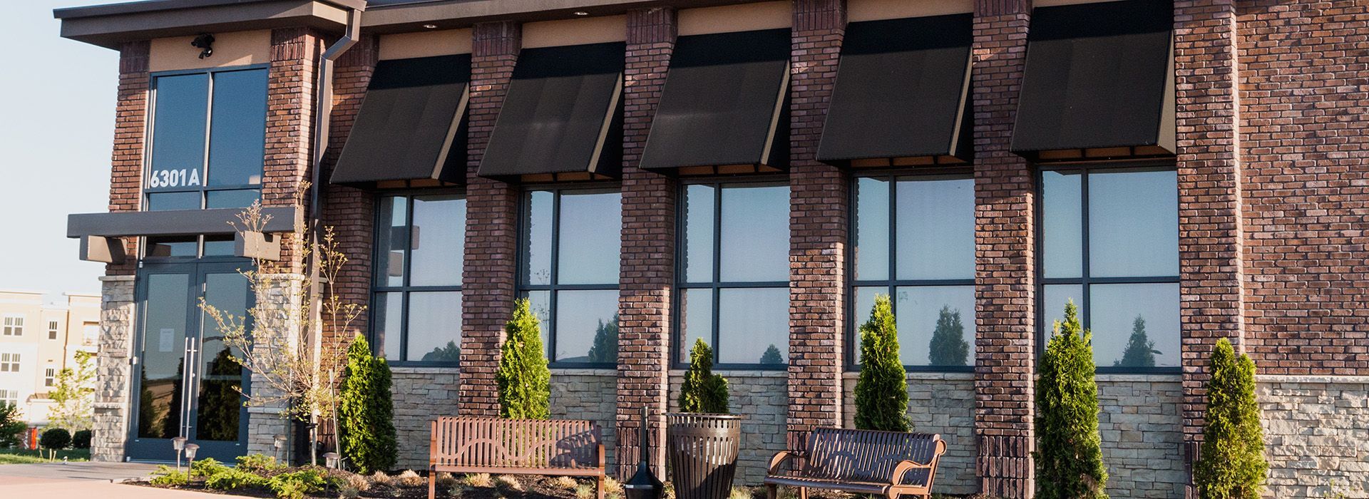 A large brick building with a lot of windows and trees in front of it.