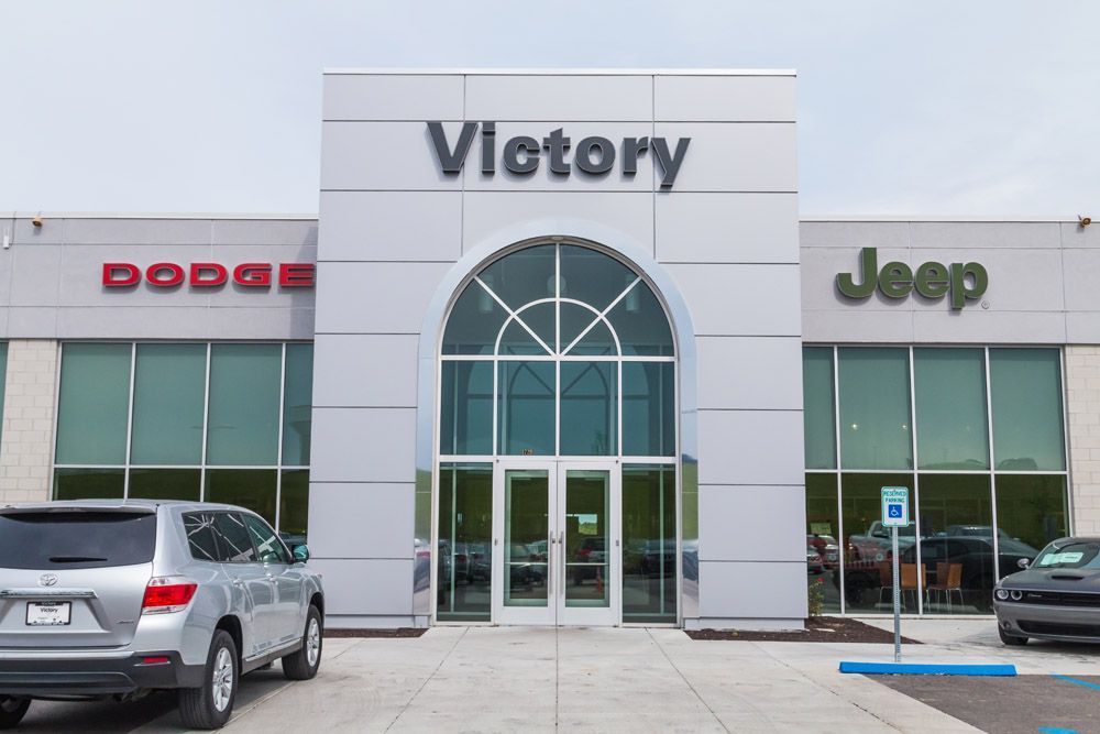 A dodge and jeep dealership with cars parked in front of it.
