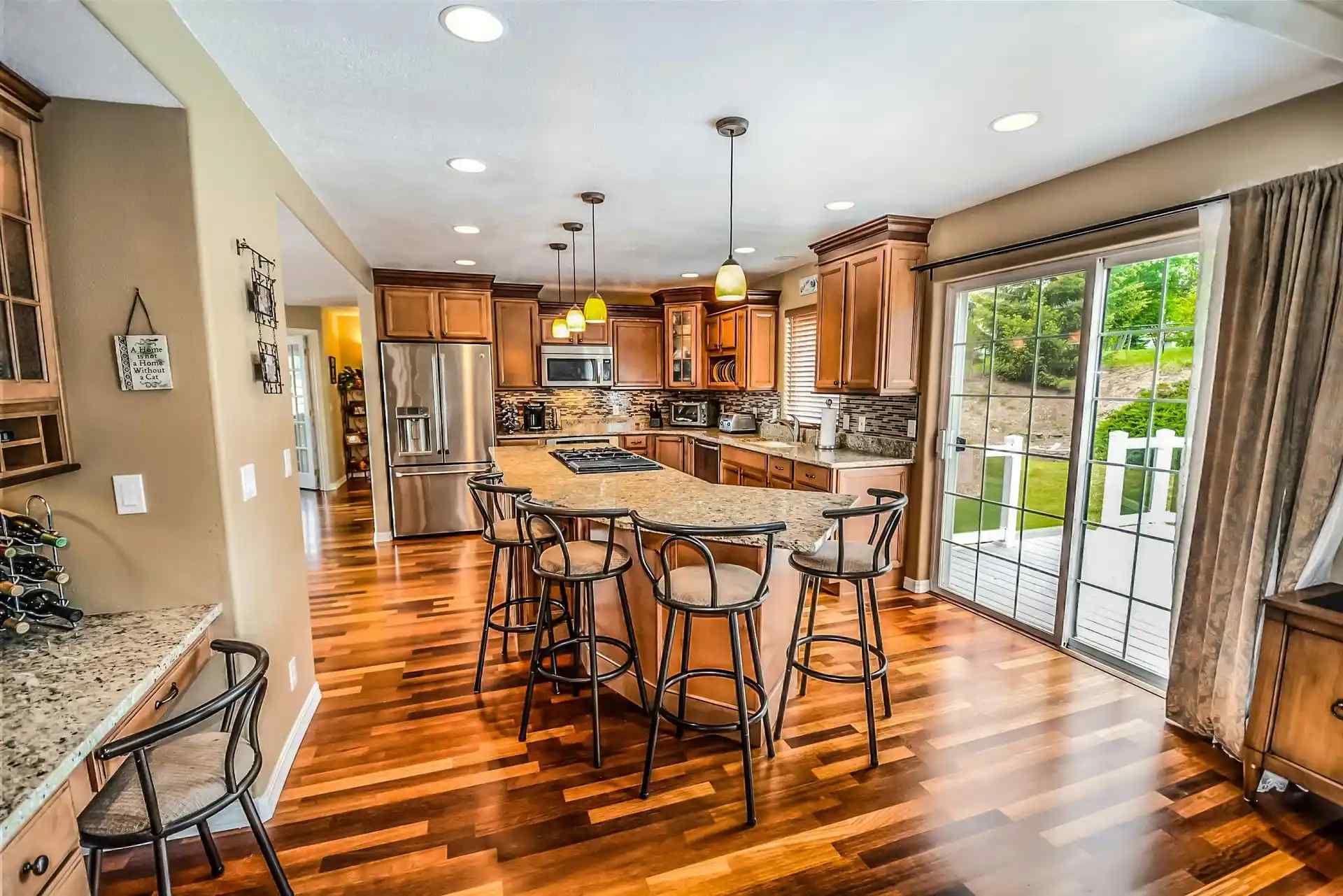 A kitchen with hardwood floors , stainless steel appliances and a large island.