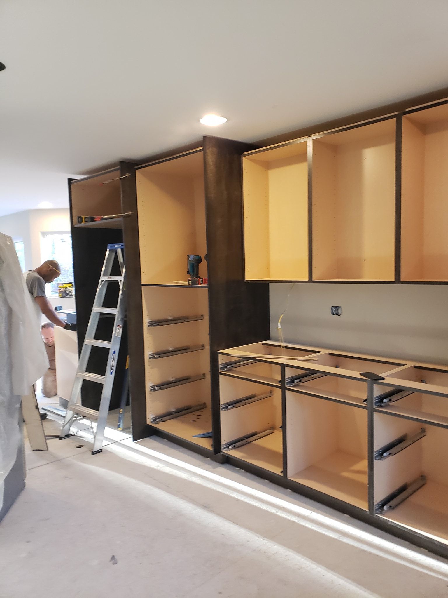 Two-story house with gray siding, two-car garage, and a wet street at sunset.