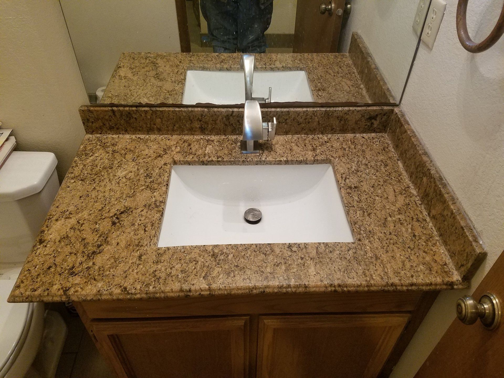 Bathroom vanity with a granite countertop, white sink, and mirror.
