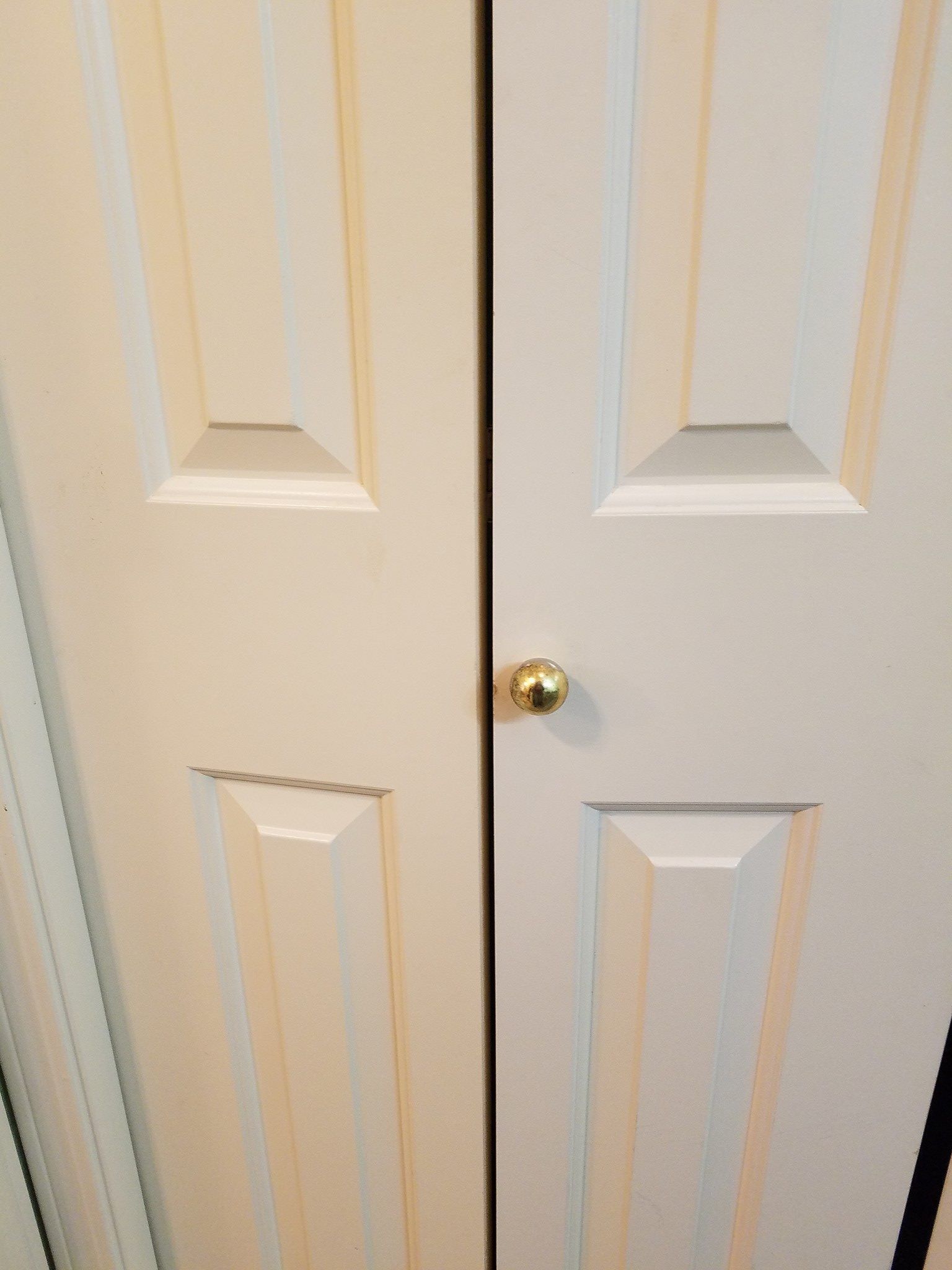 White closet doors with a gold doorknob.
