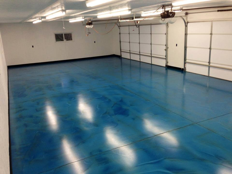 Blue metallic epoxy floor in a garage with white walls and garage doors.