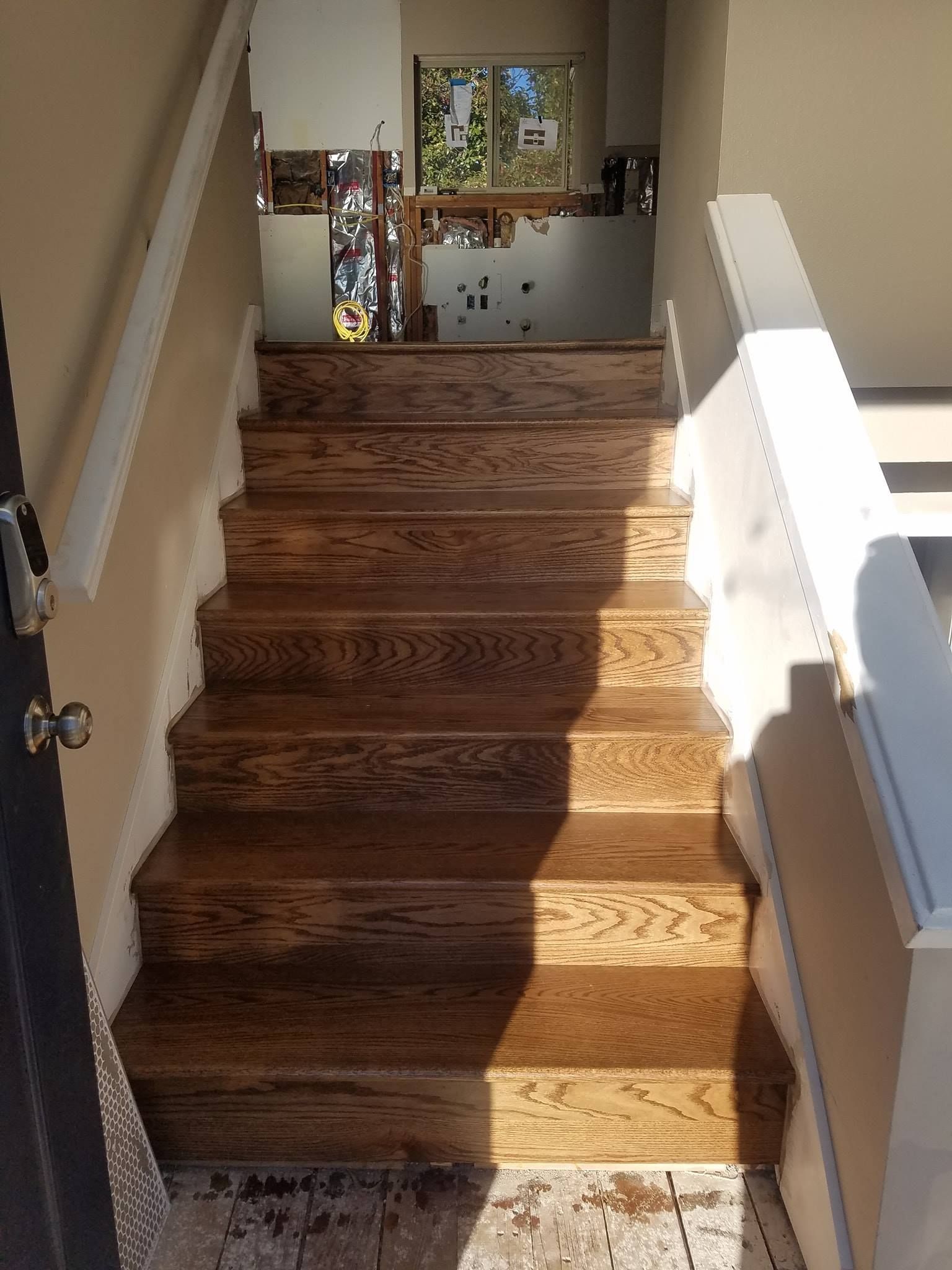 Wooden staircase leading upward. Sunlight casts shadows.