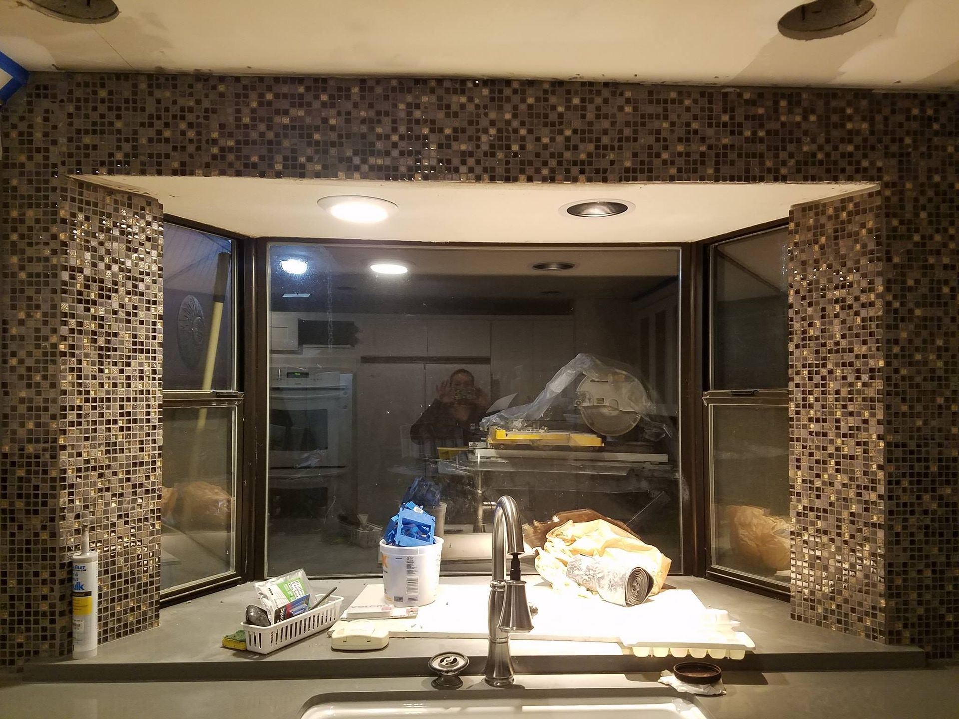 Kitchen with mosaic tile, open windows, and countertop with sink. Interior view.