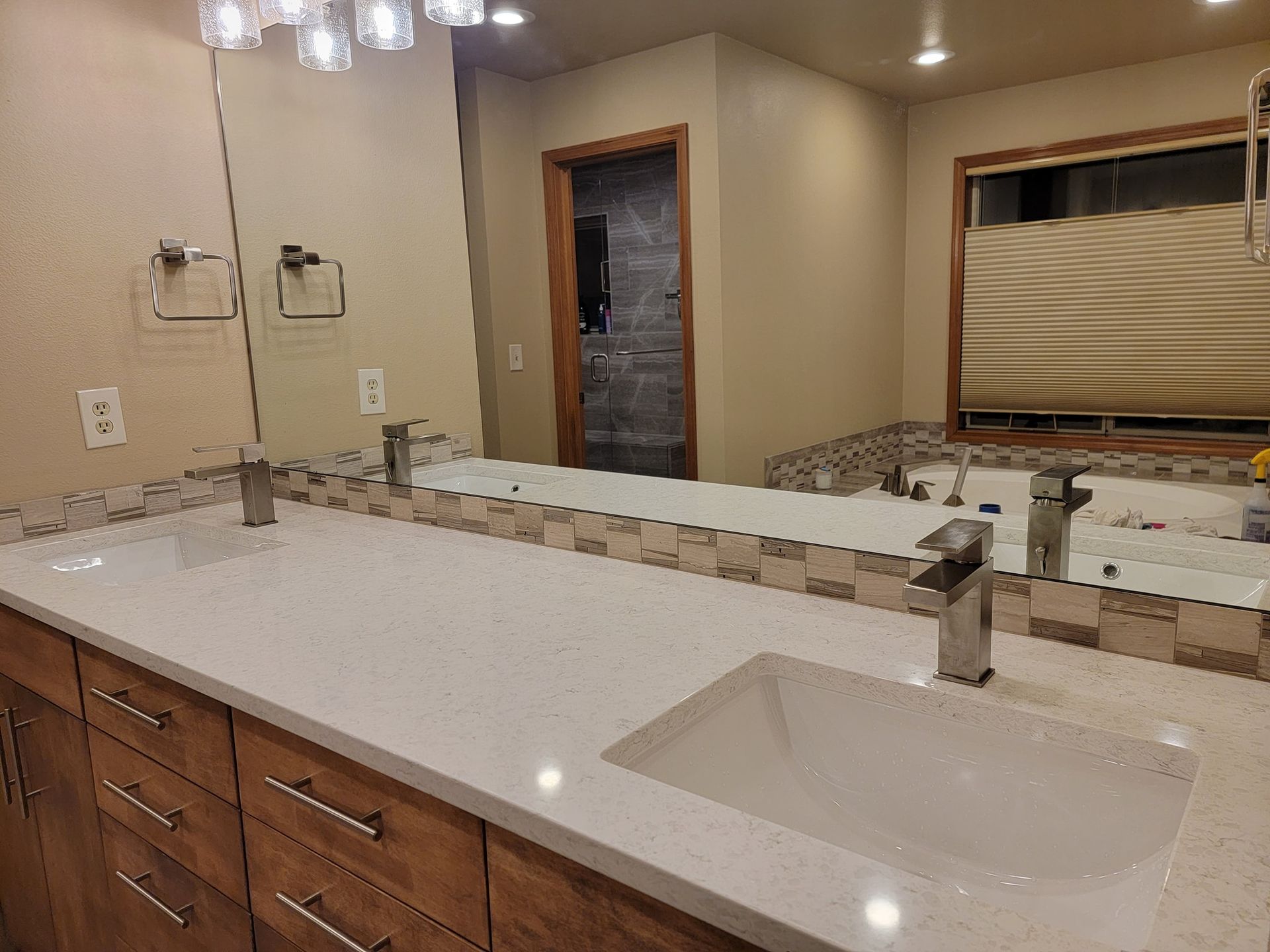 Bathroom with double sinks, light countertops, brown cabinets, and a large mirror.