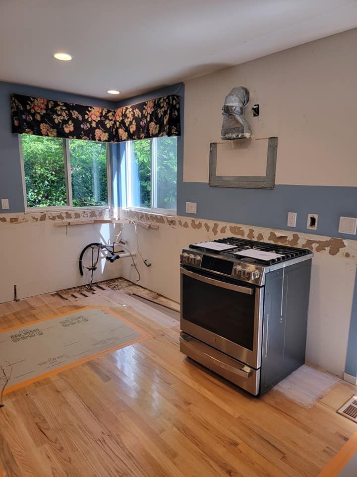 Kitchen under renovation with a stainless steel range, wood floors, and blue painted walls.