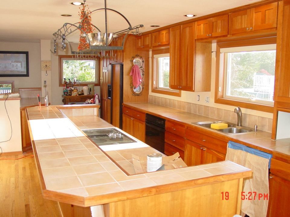 Kitchen with wooden cabinets, tile countertops, and a central island.