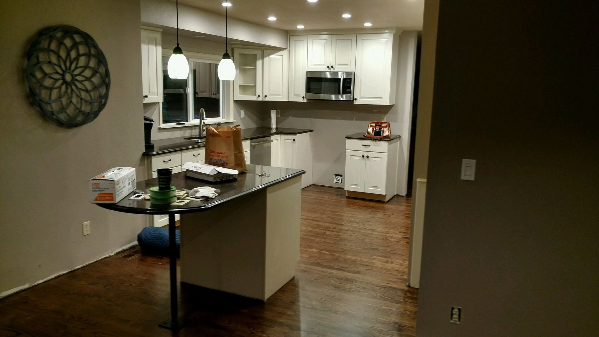 Two-story house with gray siding, two-car garage, and a wet street at sunset.
