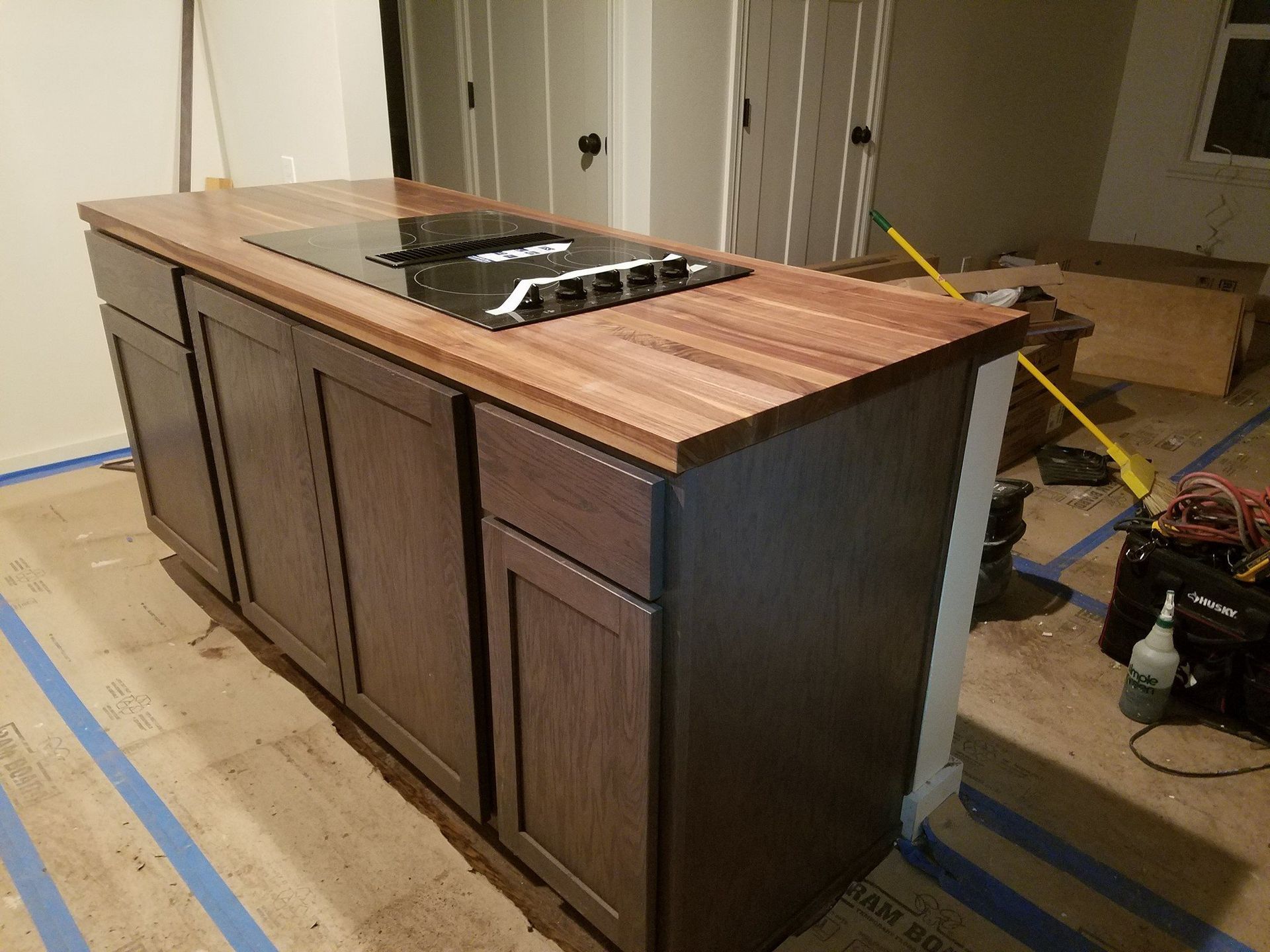 Kitchen island with a wooden countertop and cabinets, featuring a cooktop.