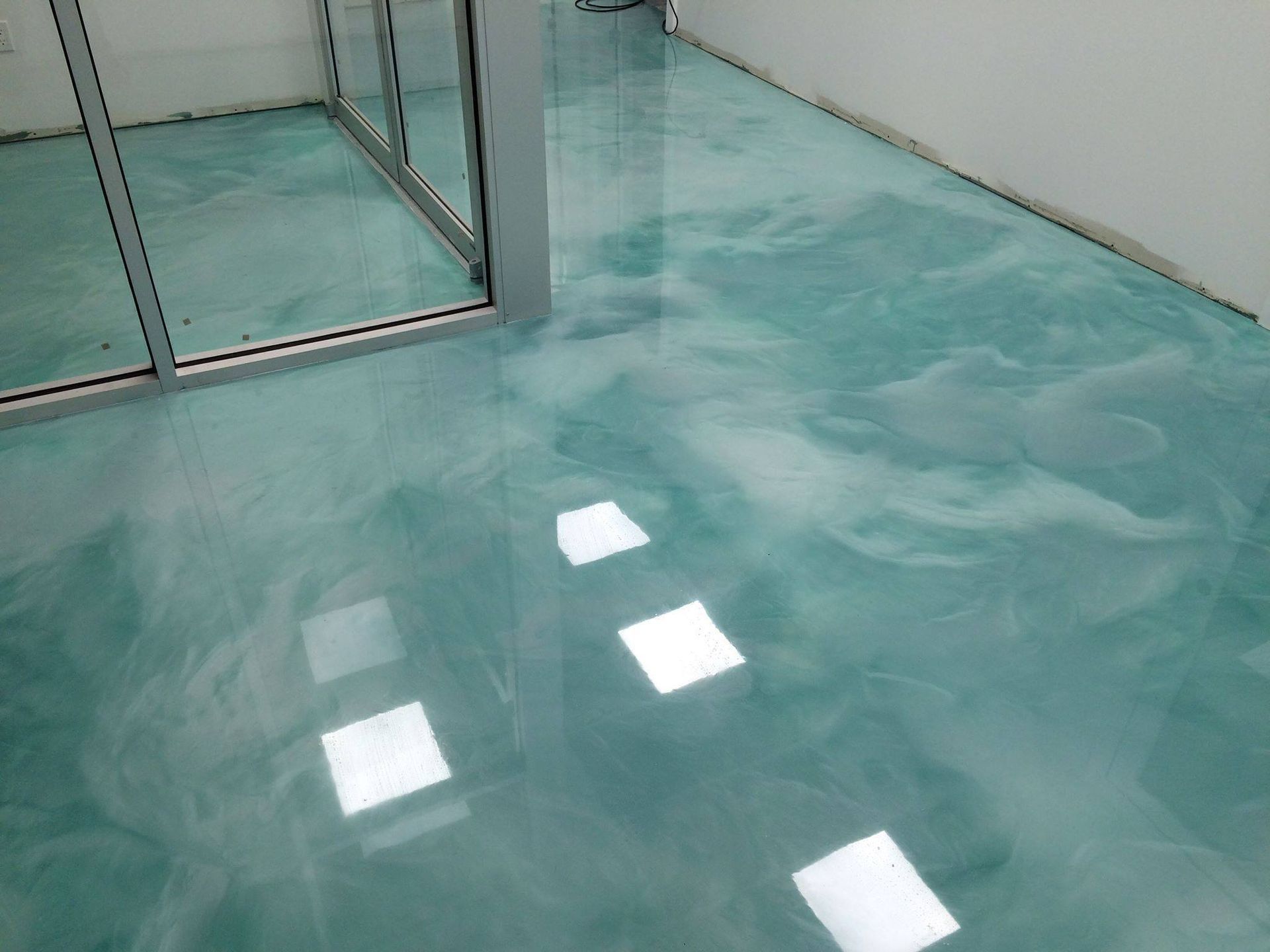Teal and white swirled epoxy flooring in a modern, well-lit interior.