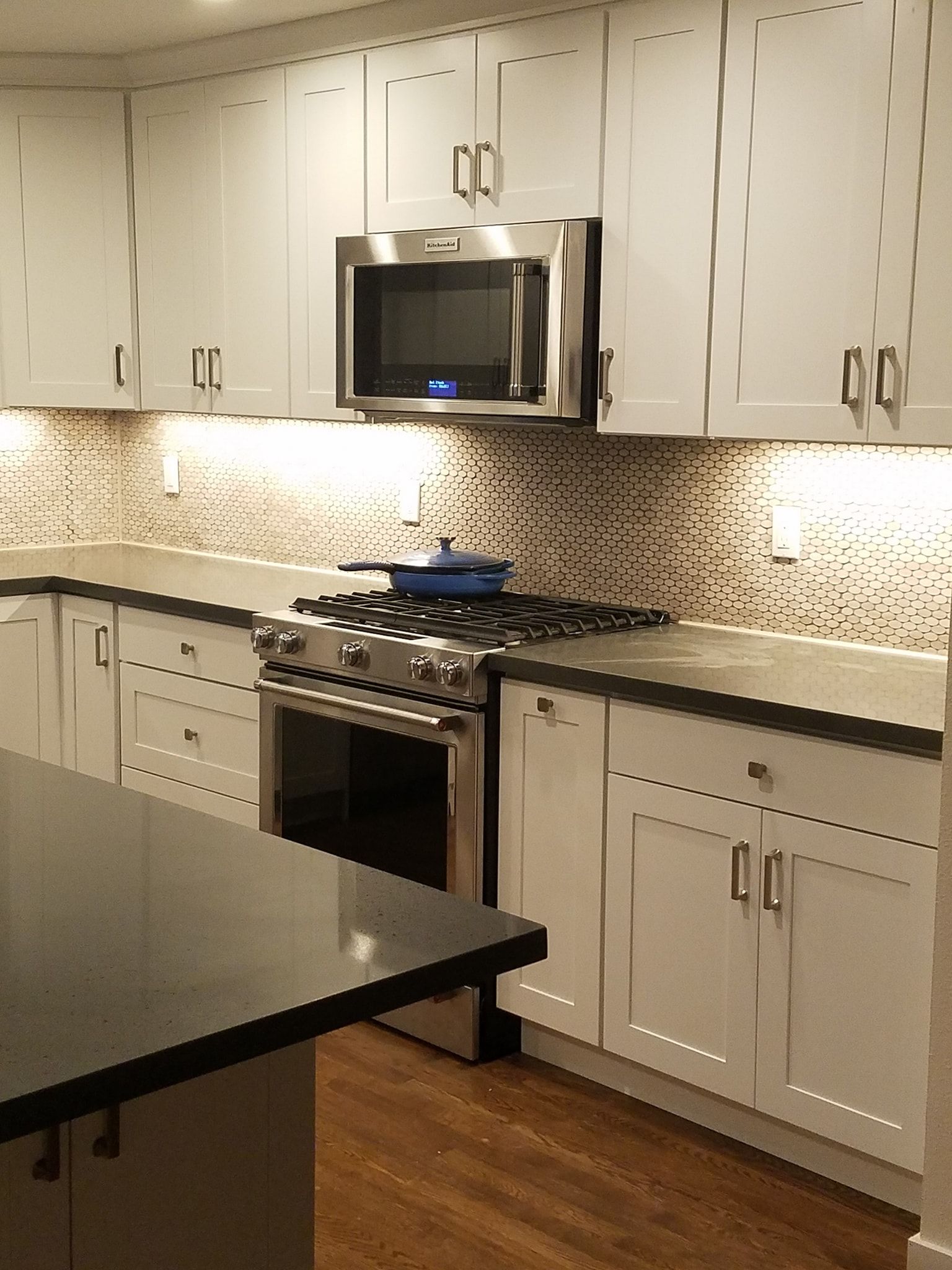 Kitchen with white cabinets, stainless steel appliances, dark countertops, and mosaic backsplash.