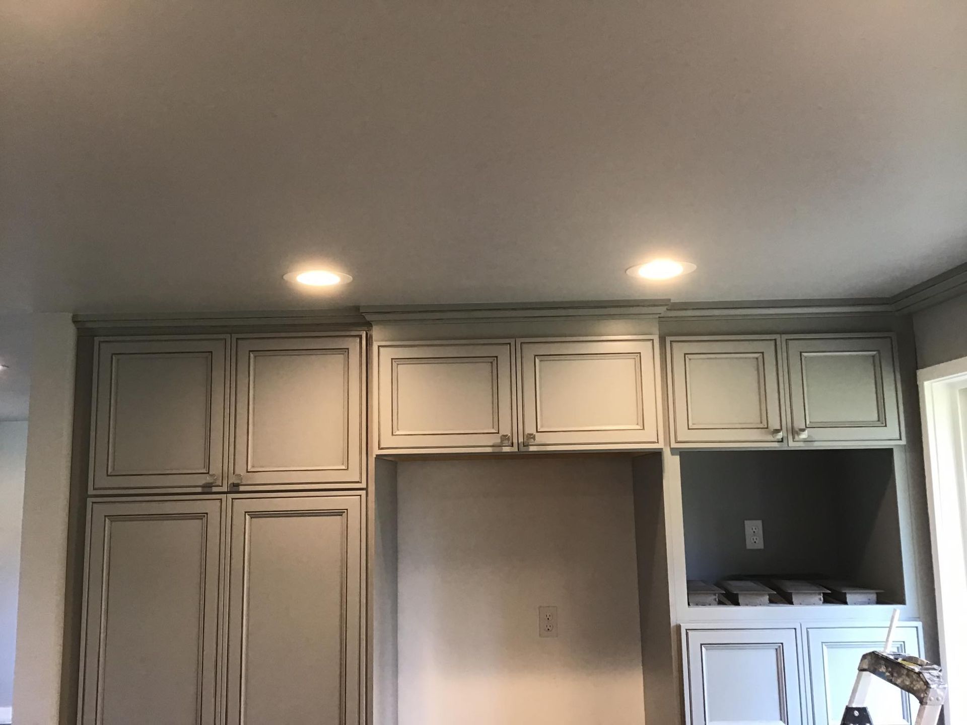 Gray kitchen cabinets with crown molding and recessed lighting.