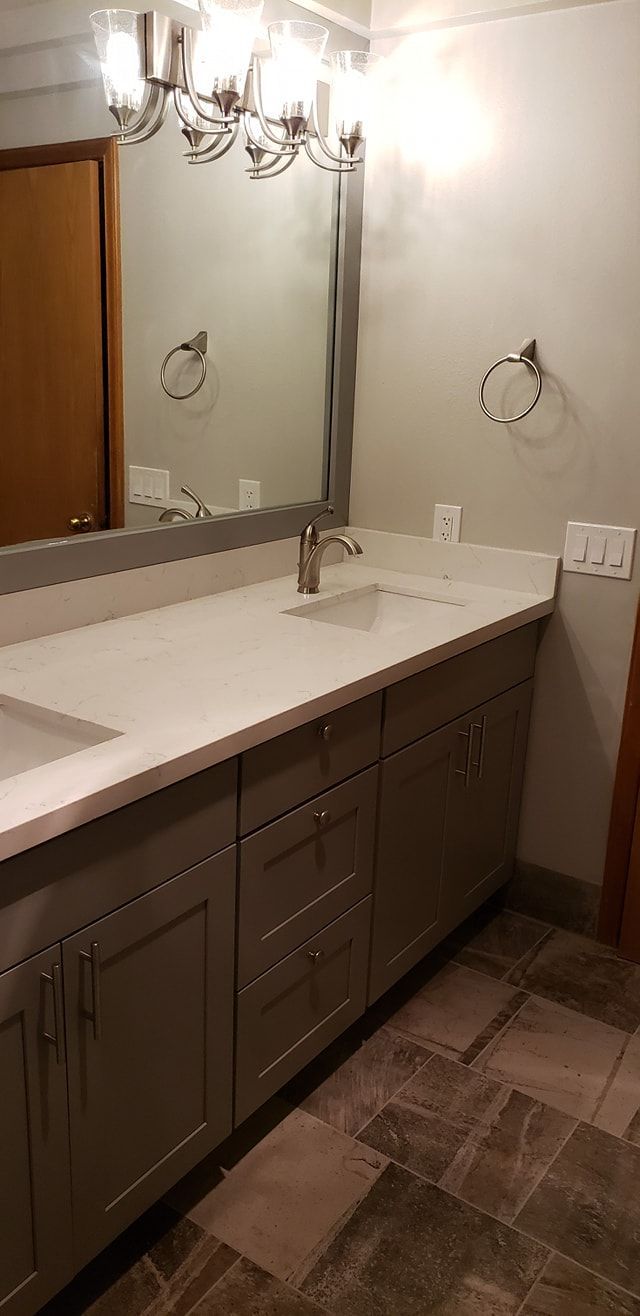 Bathroom with gray cabinets, white countertop, and a large mirror.