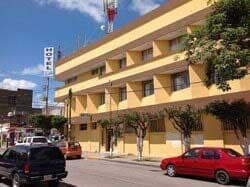 Un edificio amarillo con un coche rojo aparcado delante.
