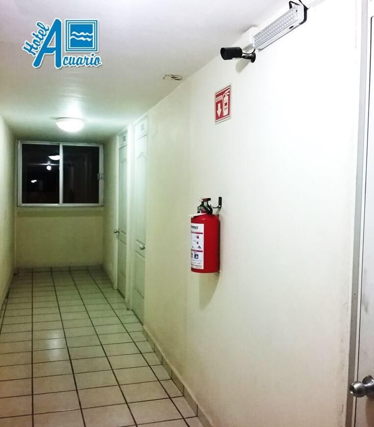 Un pasillo largo con un extintor de incendios en la pared.