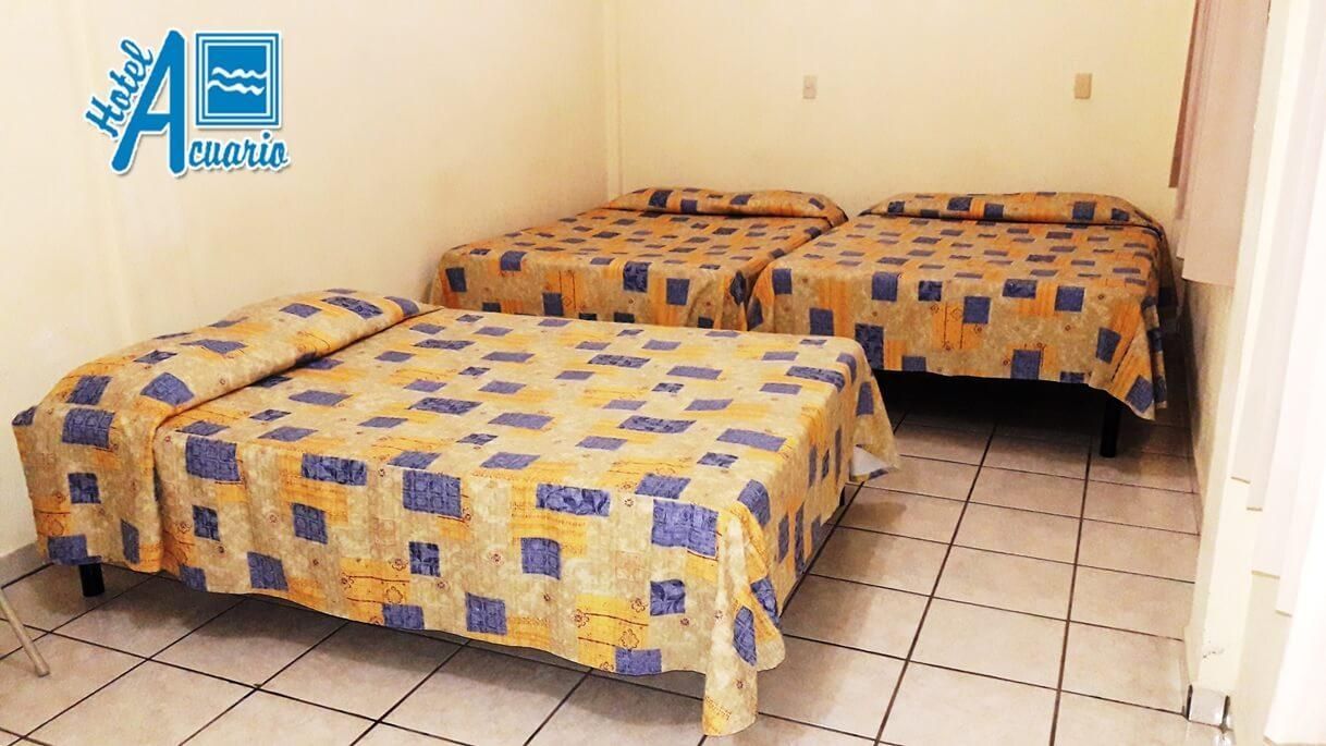 Una habitación de hotel con tres camas y un cartel que dice ae